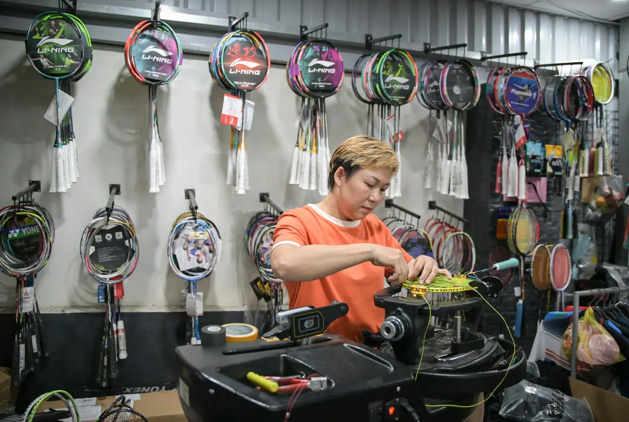Persona encordando una raqueta en una tienda deportiva